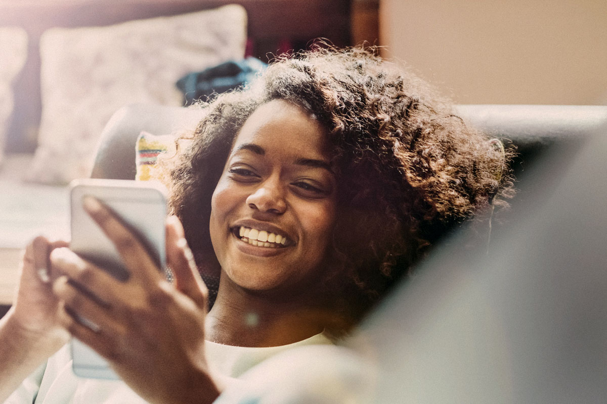 young woman using mobile phone on sofa at home