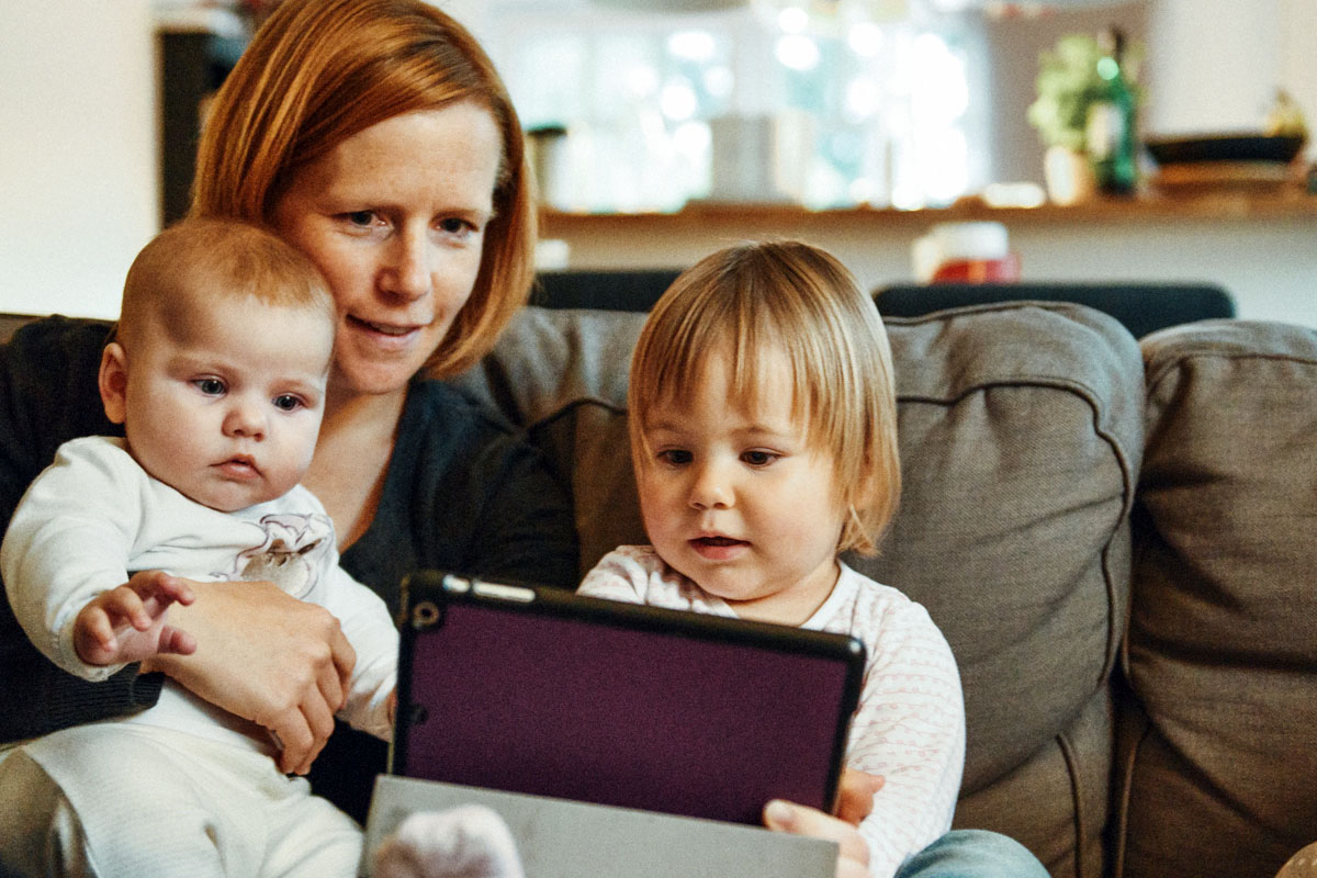Mother using tablet device with young children
