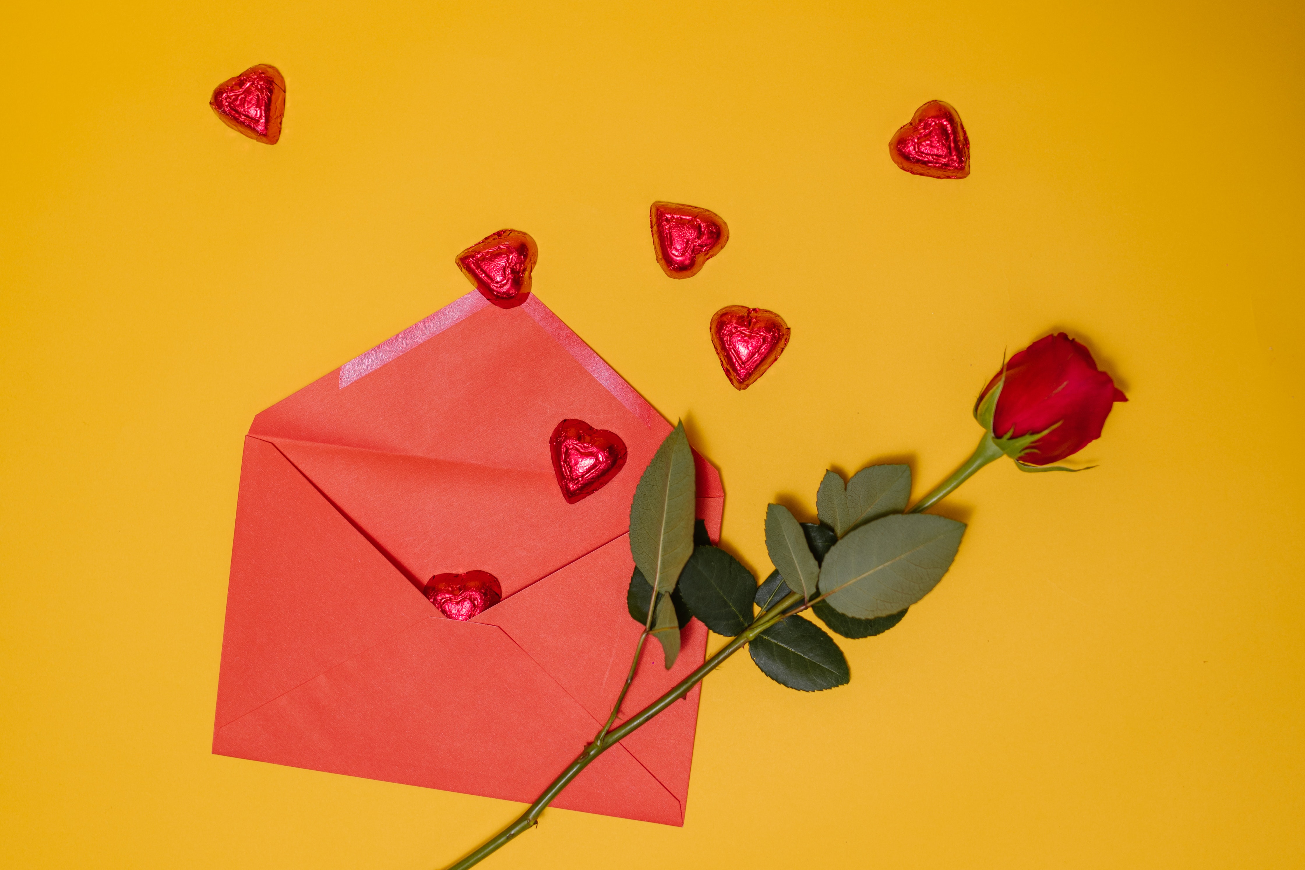 An envelope with hearsts coming out next to a red rose