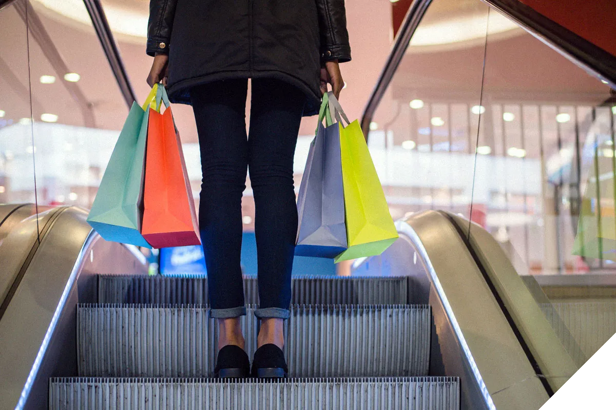 lady on escalators carrying shopping bags 